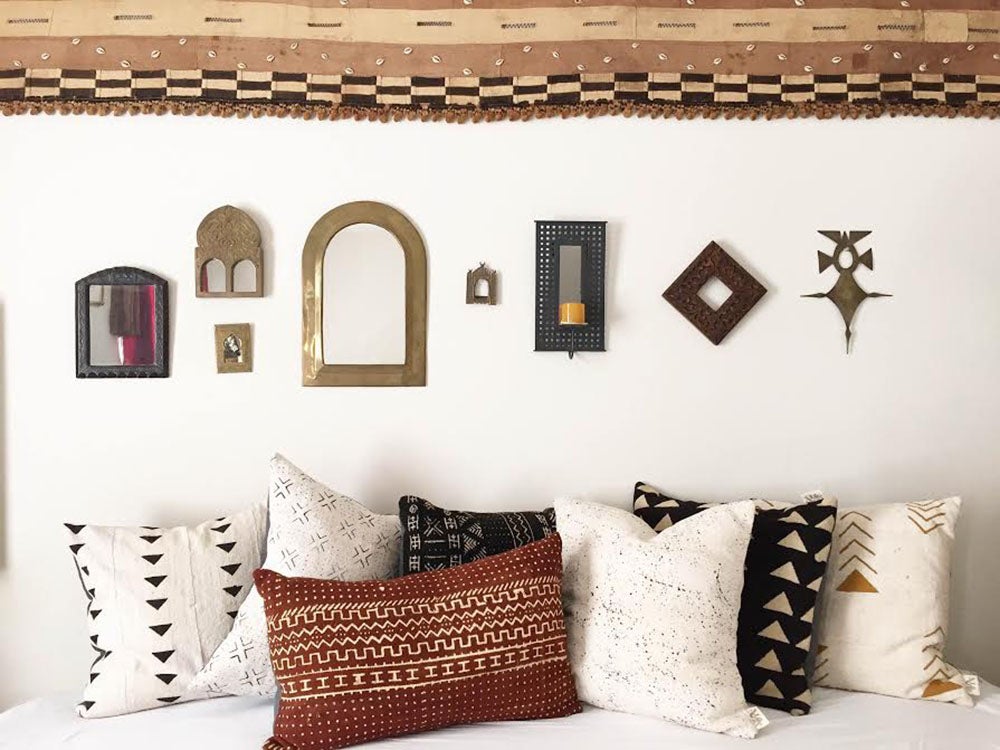 Medley of African mudcloth pillows in Sahara and bohemian inspired bedroom. African art and kuba cloth in the background.