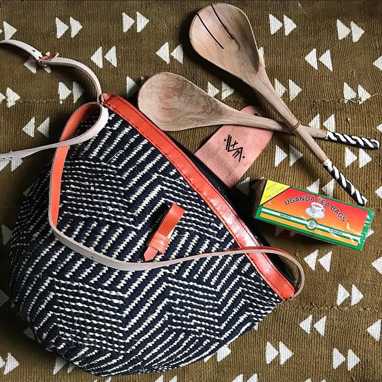 Handcrafted woven raffia and leather tote made in Uganda, Fair Trade. Perfect for daily essentials and accessorizing. Seen here with Uganda Tea and handcarved salad servers.