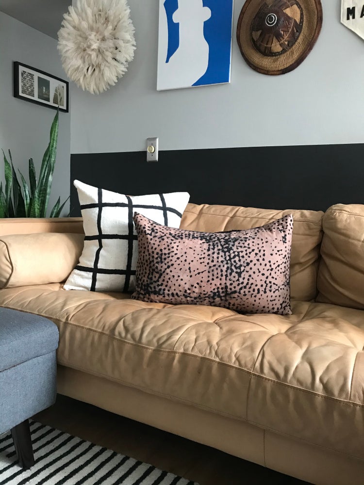 Handpainted white mudcloth pillows with minimalist designs styled on mid-century Modern sofa with batik pillow. Juju hat and African art gallery wall. Made in USA, designed in Mali.