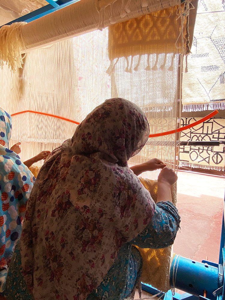 Moroccan artisan weaving a rug on the loom.