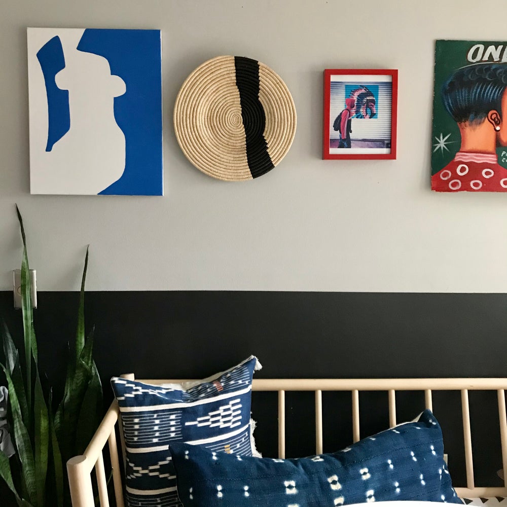 Decorative African baskets with African art on gallery wall and mudcloth pillows on a modern bench. Fair Trade made in Uganda and Rwanda.