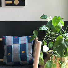 Load image into Gallery viewer, Blue Handcrafted vintage Baule pillow with accent embroidery. Ivory Coast textile and African home goods. On a modern bench with mudcloth runner on the table and African art in the background.
