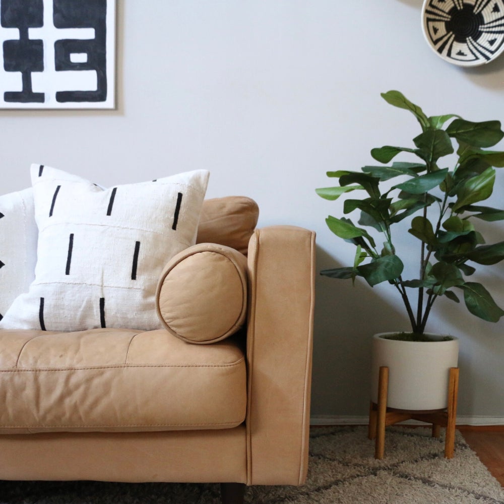 Handcrafted African mudcloth pillow in minimalist white for modern homes. Black and white seen here with African basket on leather sofa.