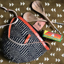 Load image into Gallery viewer, Handcrafted woven raffia and leather tote made in Uganda, Fair Trade. Perfect for daily essentials and accessorizing. Seen here with Uganda Tea and handcarved salad servers.
