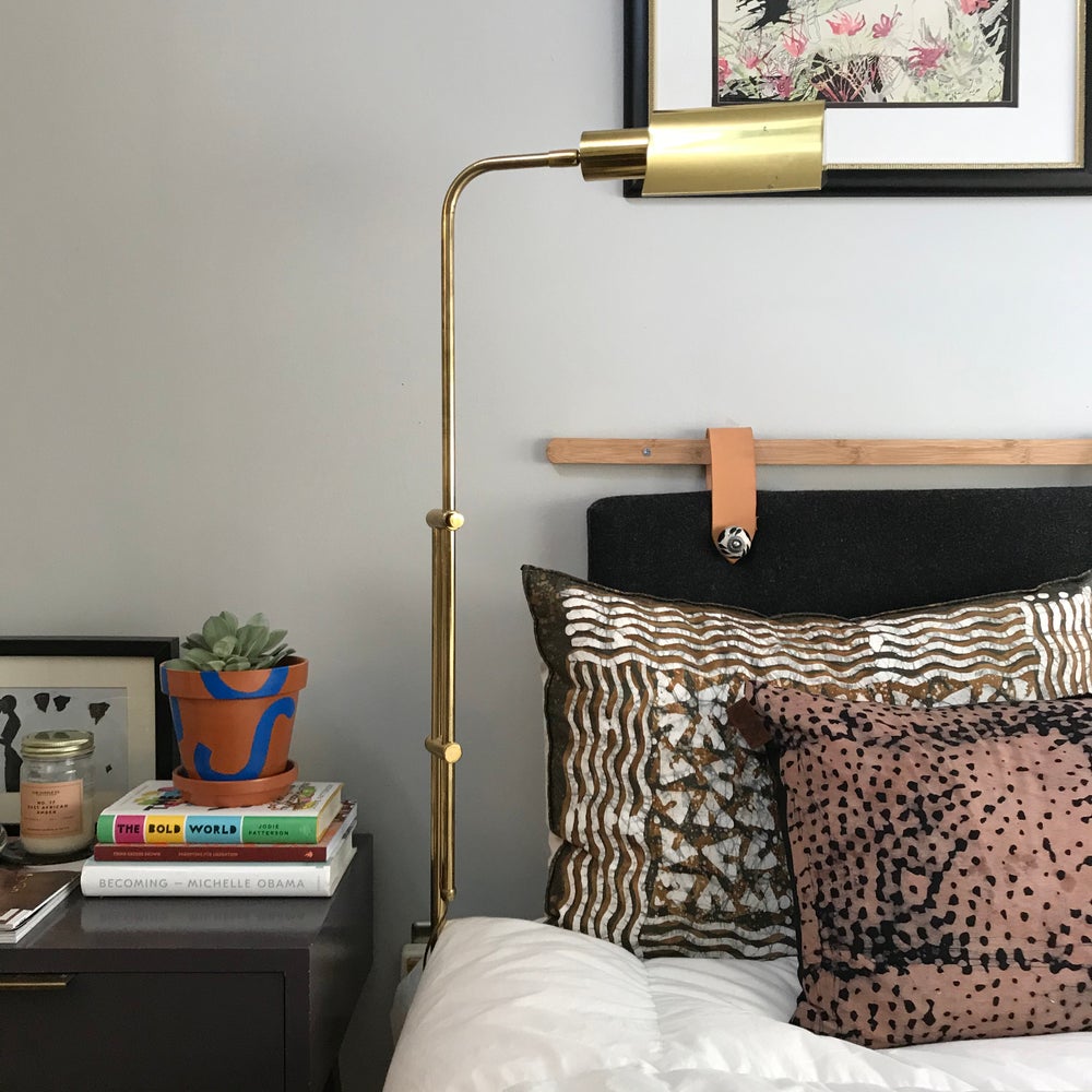 Handpainted terracotta planters with Bauhaus bohemian painted designed in blue. Perfect housewarming gift for herbs, succulents, and indoor house plants. African textile wallpaper in the background with open shelving. Seen here in electic bedroom with vintage brass envelope floorlamp.