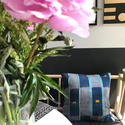 Blue Handcrafted vintage Baule pillow with accent embroidery. Ivory Coast textile and African home goods. On a modern bench with mudcloth table runner and African art in the background.