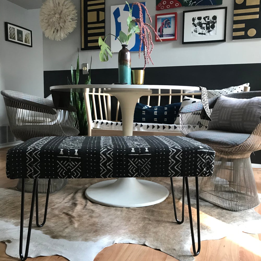 Handcrafted and minimalist mudcloth bench. Made in industrialist style with hairpin legs. African art and juju hat in background with Platner dining chairs.