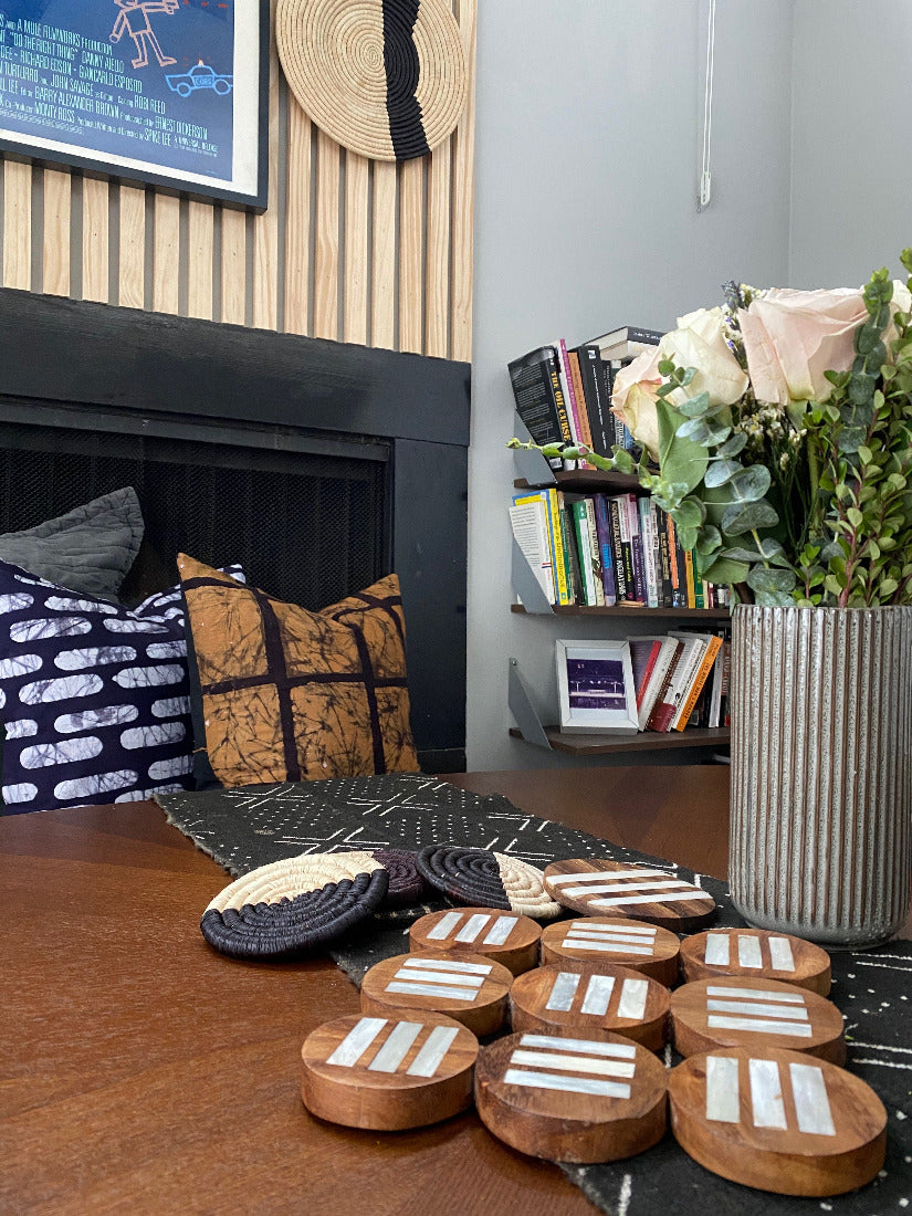 Fair Trade batik accent pillows, made in Tanzania. African basket in background with mudcloth table runner, handcrafted potholder, and woven coasters on the table.