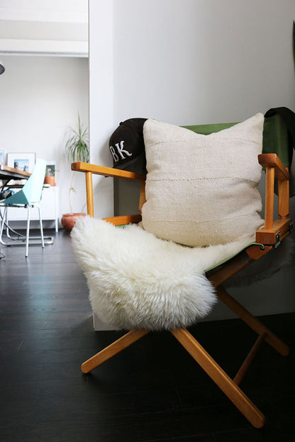 Handcrafted African mudlcoth pillow in minimalist white for modern homes. Seen in Brooklyn apartment with sheepskin.