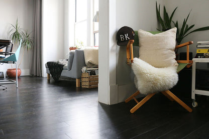 Handcrafted African mudlcoth pillow in minimalist white for modern homes. Seen in Brooklyn apartment with sheepskin.