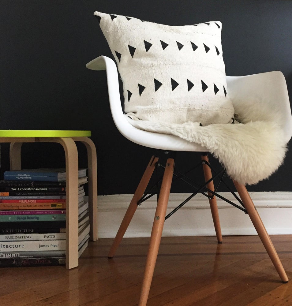 Handcrafted African mudcloth pillow in minimalist white for modern homes. Black and white seen here in Eames chair sheepskin rugs.