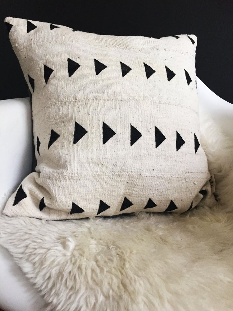 Handcrafted African mudcloth pillow in minimalist white for modern homes. Black and white seen here in Eames chair sheepskin rugs.