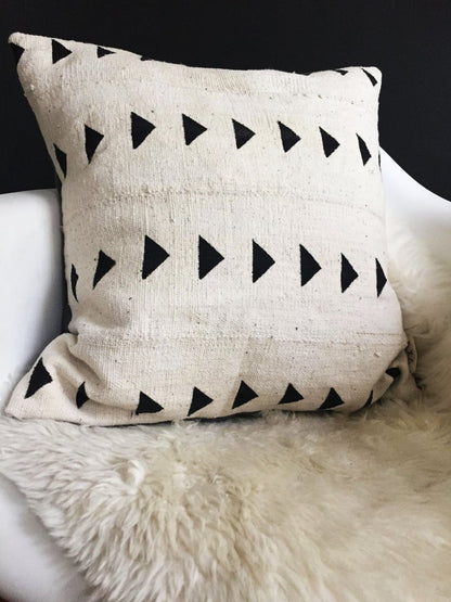 Handcrafted African mudcloth pillow in minimalist white for modern homes. Black and white seen here in Eames chair sheepskin rugs.